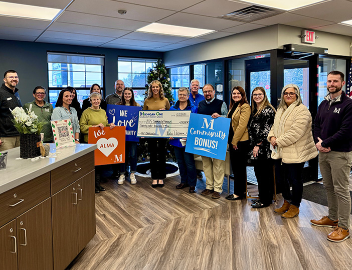M1 Credit Union staff and Alma community members gathered in the branch lobby celebrating the Community Bonus event with smiles and local engagement.
